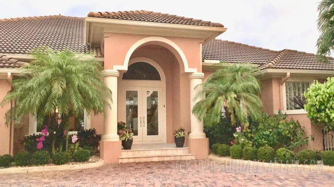 Beautiful Orchids Attached to Palm Trees In Front of Stunning Mediterranean Style Home