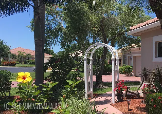 Charming white arbor over walkway next to flowering bougainvillea in tropical setting