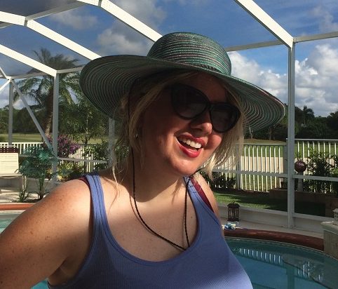 Happy smiling woman in a hat by the pool