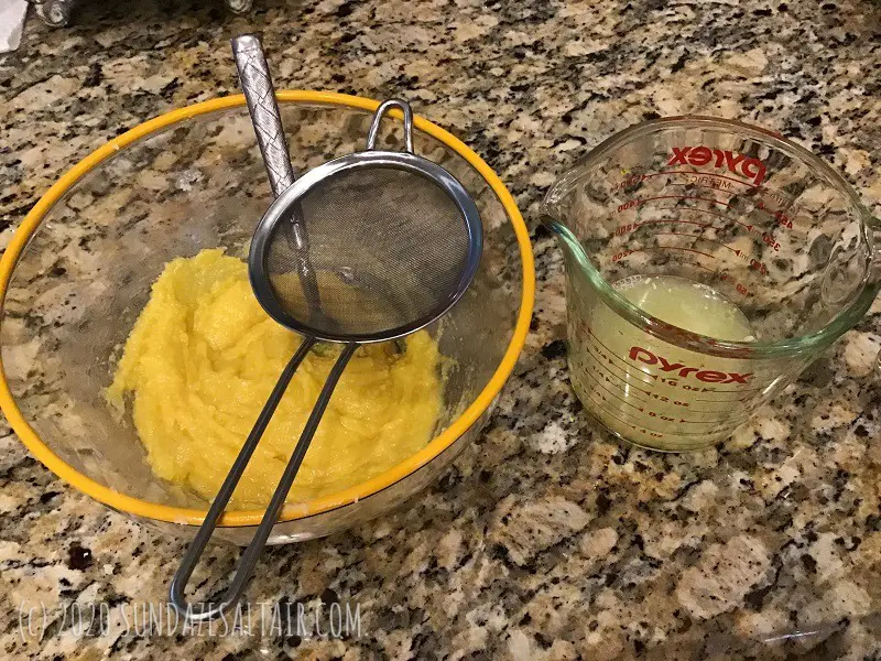 Lemon Juice Getting Strained Into Lemon Pudding Cake Custard Batter In Bowl