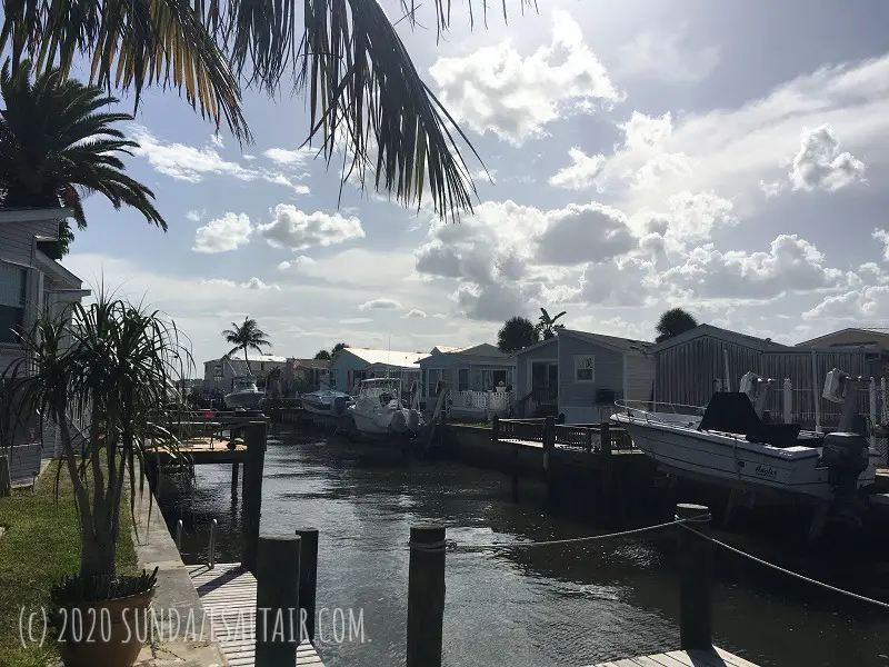 Summer Bungalow Homes With Boats Docked On the Water Under Palm Trees