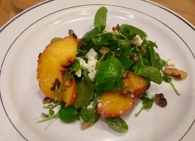 Watercress And Sauteed Peach Salad On White Plate