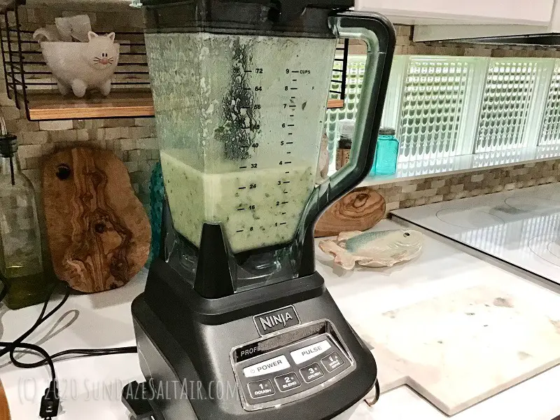 Watercress Soup In Ninja Blender In Front Of Basketweave Backsplash, Olive Wood Cutting Boards, Teal Glass Salt And Pepper Shakers