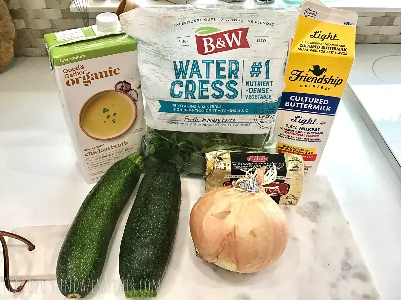 Watercress Zucchini Soup Ingredients On Marble Cutting Board In Front Of Basket Weave Backsplash