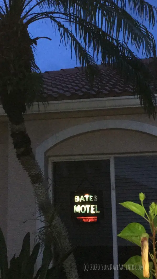 Bates Motel Sign Lit Up Hanging In Window Under Palm Tree At Dusk
