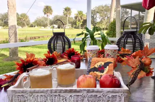 Homemade Warm Caramel Apple Cider Like Starbucks On Wooden Tray Surrounded By Fall Garland Overlooking Beautiful Lake And Scenery