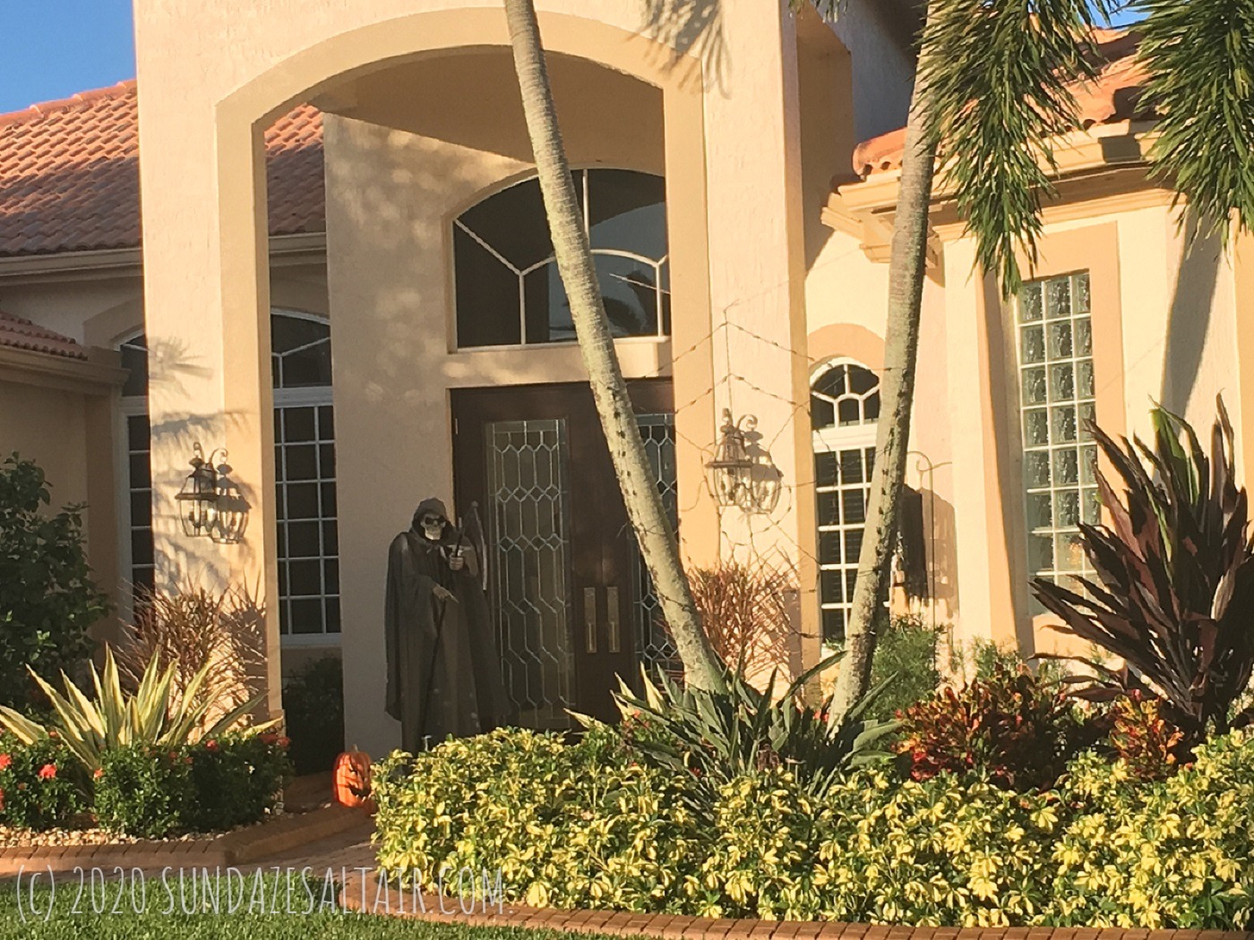 Spooky Angel Of Death With Scythe Halloween Decor Next To Front Door And Grinning Pumpkin