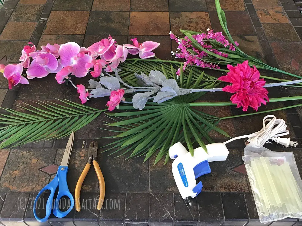 How to make a tropical wreath - some of the materials you will need including tropical greenery, flowers, wire cutters, scissors, & a hot glue gun