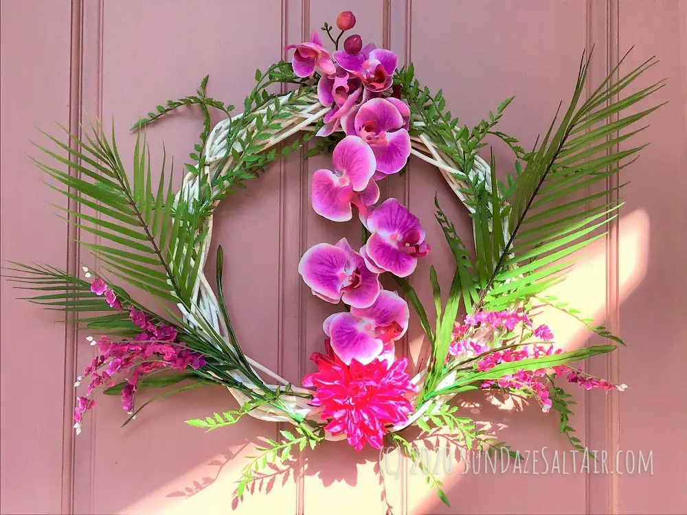 Beautiful, colorful tropical island-inspired wreath hanging against pink door