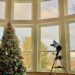 How To Decorate A Room With High Ceilings For Christmas--Flocked Christmas Tree Overlooks Picture Window Panoramic View Of Bay In Winter